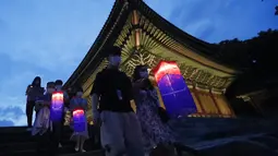 Pengunjung memegang lentera tradisional Korea berjalan-jalan selama Tur Cahaya Bulan di Istana Changdeokgung di Seoul, Korea Selatan, Kamis, (13/8/2020). Istana dibuka kembali pada Kamis setelah ditutup selama dua bulan karena pandemi Covid-19. (AP Photo/Ahn Young-joon)