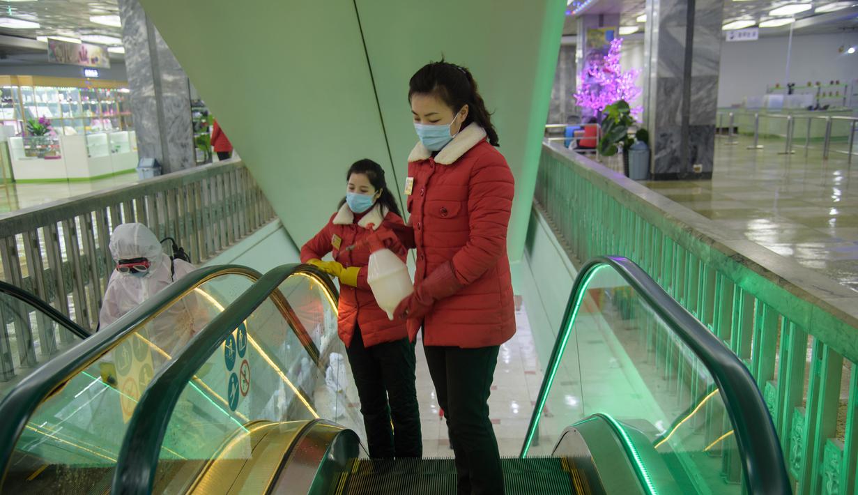 Petugas melakukan penyemprotan cairan desinfetan pada tangga eskalator di Pyongyang Department Store No. 1, di Pyongyang, Korea Utara, Senin (28/12/2020). (AFP/Kim Won Jin)