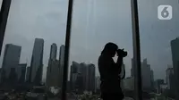 Seorang pria mengambil gambar suasana gedung bertingkat di kawsan Jakarta, Kamis (26/12/2019). Pemerintah memproyeksi pertumbuhan ekonomi tahun depan di kisaran 5,2%, berada di bawah target APBN 2020 sebesar 5,3%.  (Liputan6.com/Angga Yuniar)