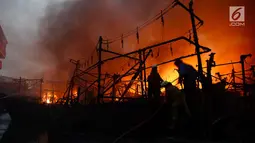 Petugas damkar berusaha menjinakan api yang membakar kapal nelayan di Pelabuhan Muara Baru, Penjaringan, Jakarta Utara, Sabtu (23/2). Belasan mobil damkar dikerahkan untuk memadamkan api. (merdeka.com/Imam Bukhori)