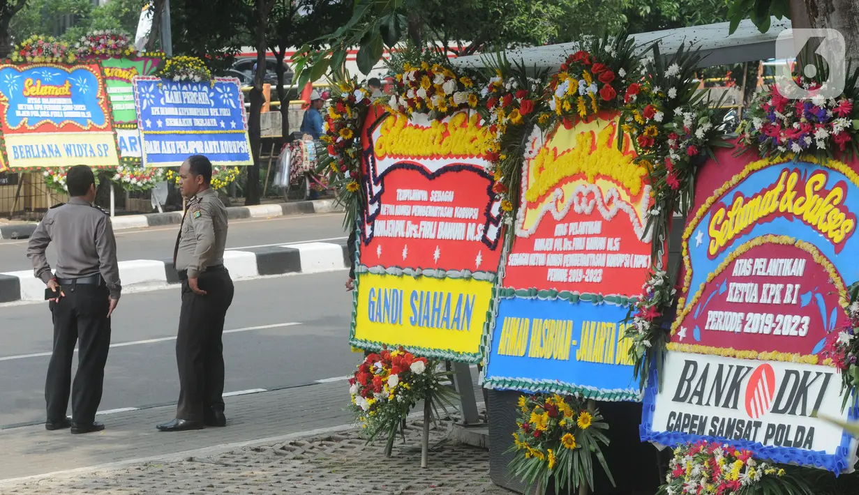 Petugas kepolisian berdiri di dekat karangan bunga ucapan selamat yang berjejer di sekitar Gedung Merah Putih KPK, Jakarta, Jumat (20/12/2019). Papan karangan bunga tersebut berisi ucapan selamat terhadap dilantiknya pimpinan KPK periode 2019-2023. (merdeka.com/Imam Buhori)