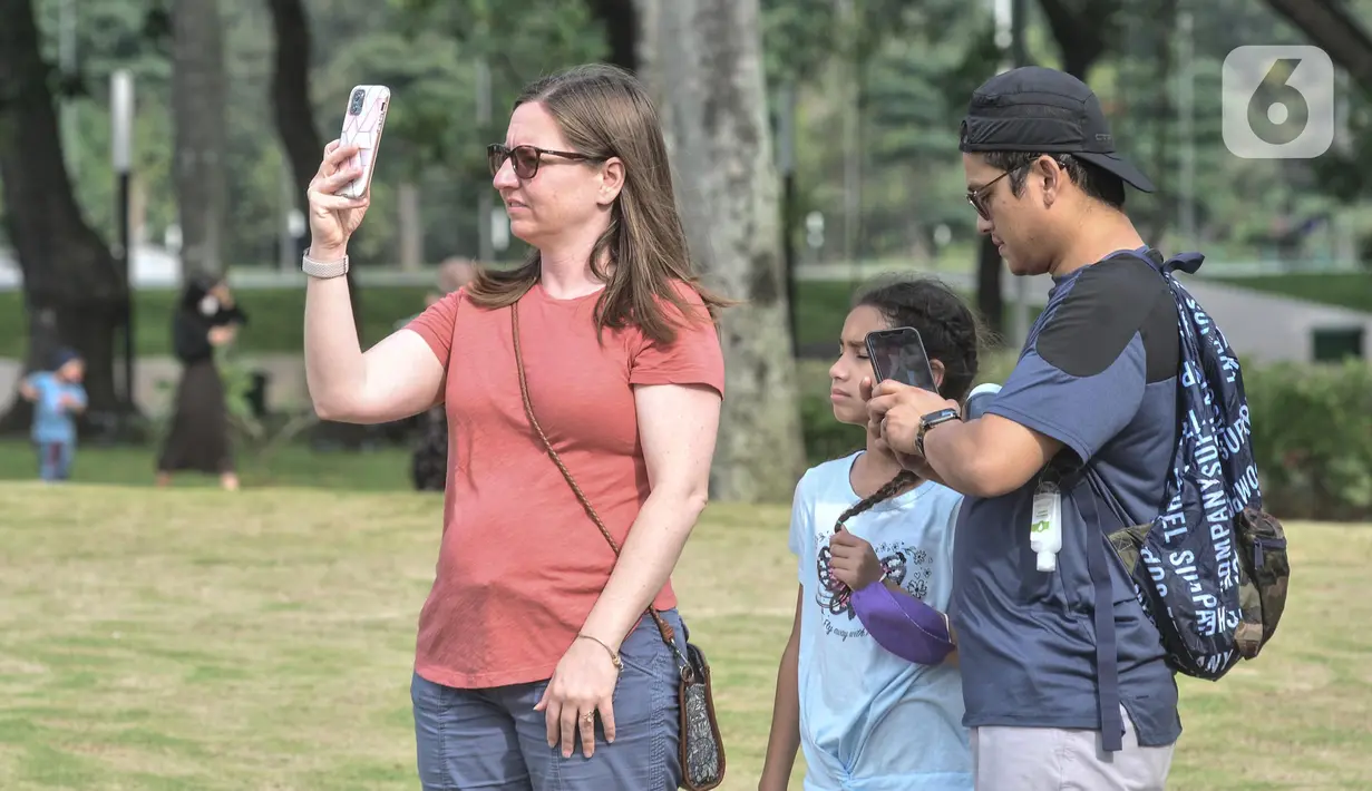 Wisatawan asing mengabadikan Tugu Monas melalui smartphone di Jakarta Pusat, Kamis (16/6/2022). Pasca ditutup sejak 2020 akibat pandemi Covid-19, Pemerintah Provinsi DKI Jakarta melakukan uji coba pembukaan kawasan wisata Monas secara bertahap dan terbatas yang dimulai dari kawasan luar tugu. (merdeka.com/Iqbal S Nugroho)