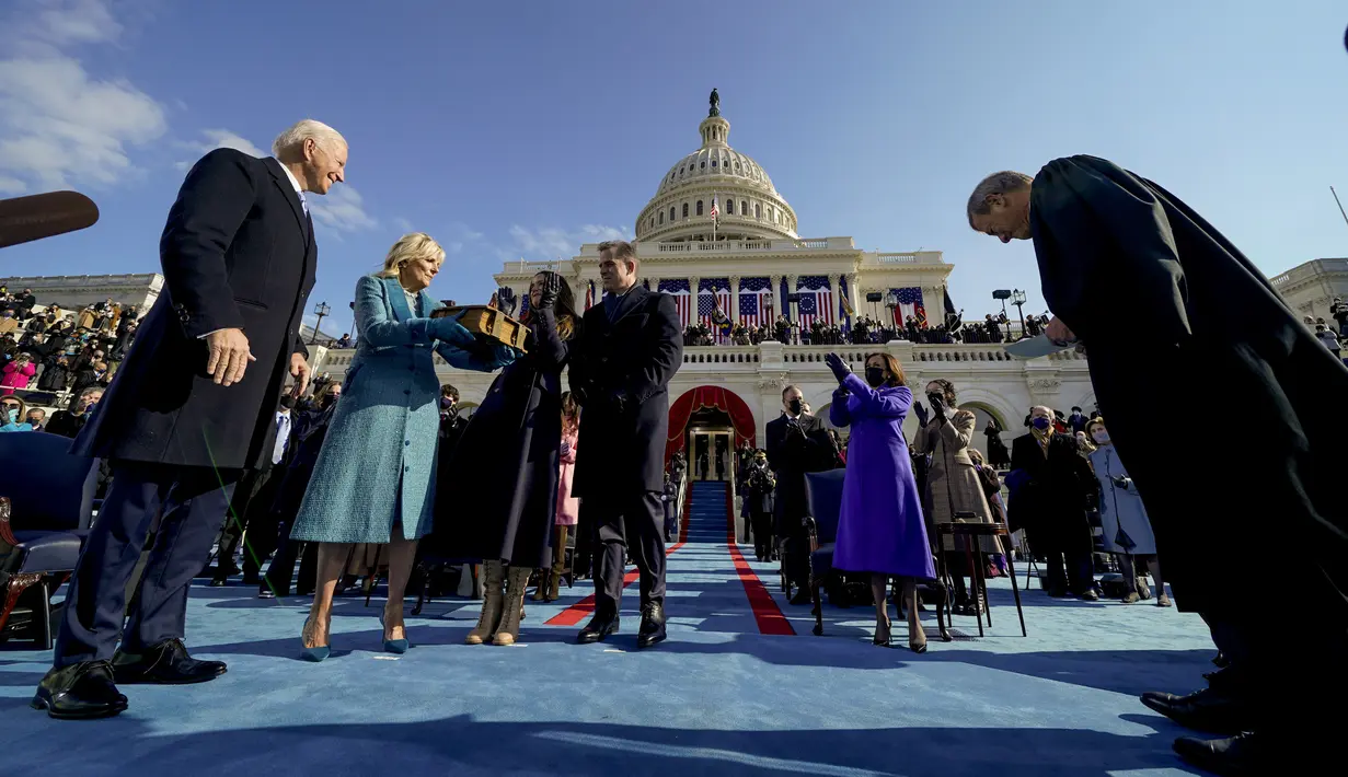 Presiden AS Joe Biden diberi selamat oleh ibu negara Jill Biden, putranya Hunter Biden, dan putrinya Ashley Biden setelah dilantik Ketua Mahkamah Agung John Roberts di Capitol AS di Washington, Rabu (20/1/2021). Wakil Presiden Kamala Harris bertepuk tangan di kanan atas. (AP Photo/Andrew Harnik)