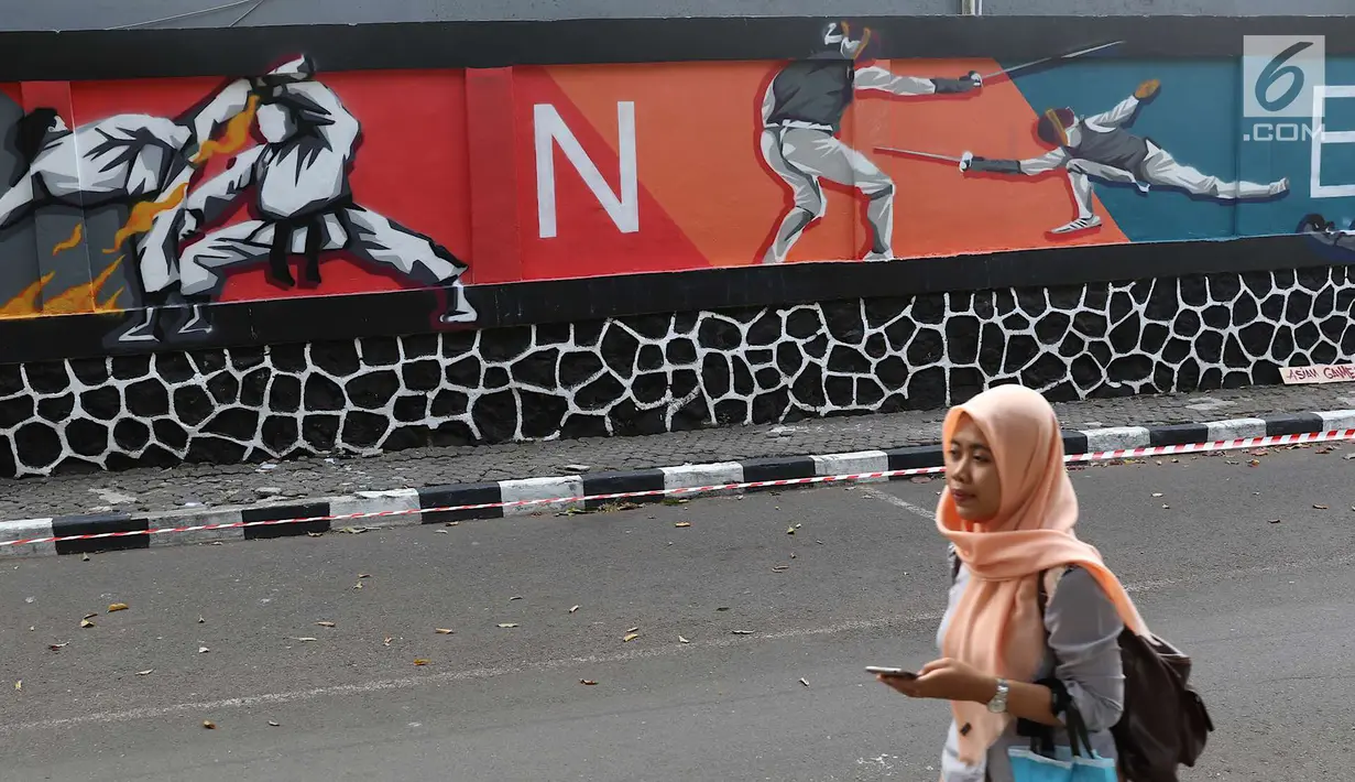 Mahasiswa melintas di depan mural bertema Asian Games 2018 di kawasan Universitas Negeri Jakarta, Kamis (16/8). Mural karya mahasiswa seni rupa tersebut dibuat dalam rangka menyambut Asian Games 2018. (Liputan6.com/Immanuel Antonius)
