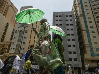 Jemaah haji menggunakan payung untuk melindungi diri dari terik matahari saat berjalan di kota suci Mekkah pada 23 Juni 2023.  (Photo by Sajjad HUSSAIN / AFP)