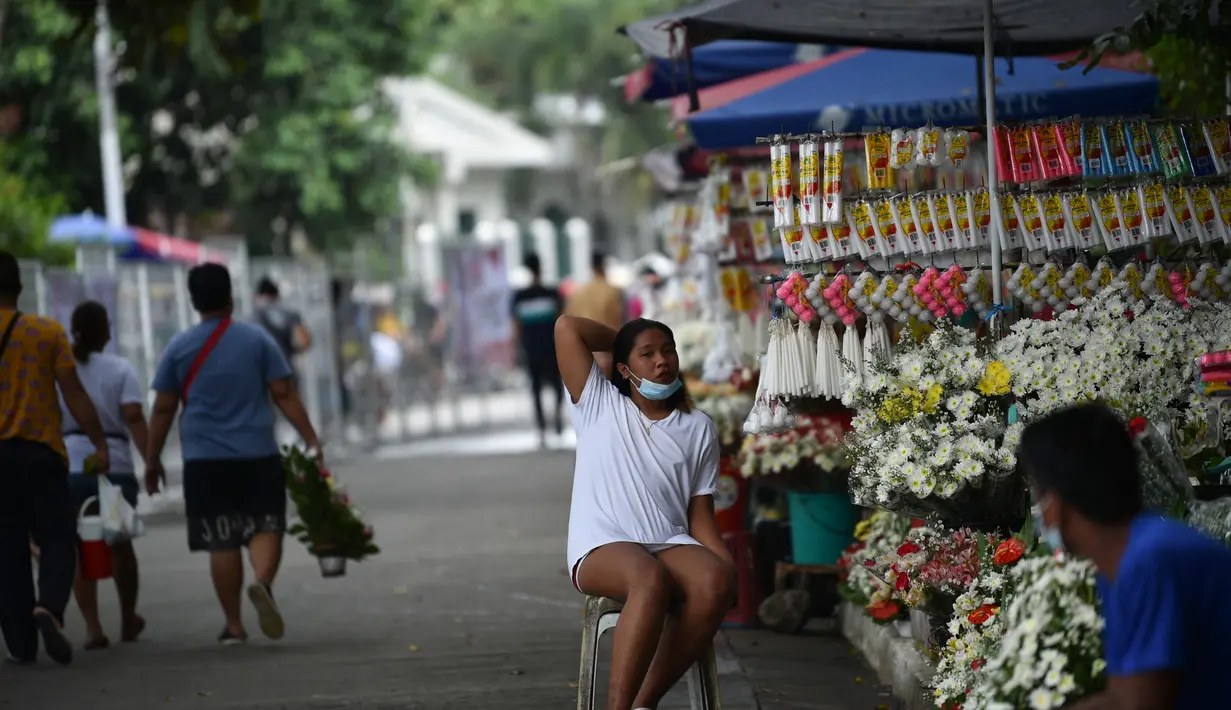Penjual bunga menunggu pelanggan di dekat pemakaman di Manila, Filipina (28/10/2021). Pemerintah setempat akan menutup pemakaman nasional untuk Hari Semua Orang Kudus karena pandemi virus corona Covid-19. (AFP/Ted Aljibe)