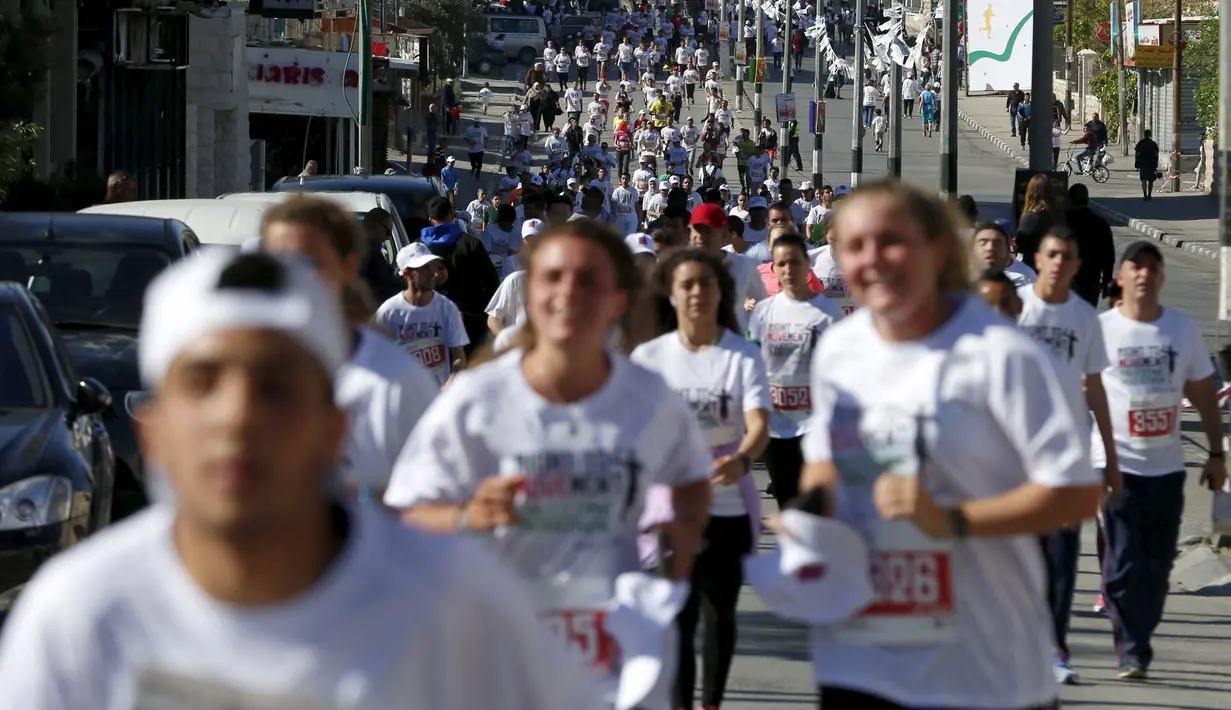 Sejumlah peserta berlari menyusuri tembok pemisah Israel selama Right to Movement Maraton di kota Bethlehem, Palestina, Jumat (1/4). Tembok sejauh 700 km ini dijadikan obyek berlari para peserta. (REUTERS / Ammar Awad)