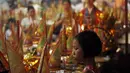 Hungry Ghost merupakan kepercayaan saat gerbang neraka terbuka untuk membiarkan roh-roh yang berkeliaran di negeri orang hidup mencari makanan. Seorang anak menghiasi persembahan di festival Hungry Ghost, Kuala Lumpur, (3/8/2014). (REUTERS/Olivia Harris)