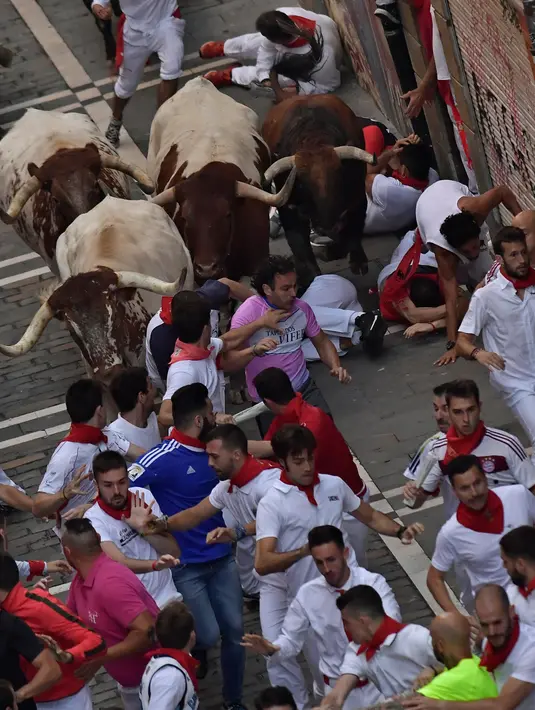Sejumlah peserta terjatuh saat diseruduk banteng selama hari ketiga Festival San Fermin di Pamplona, Spanyol utara, (9/7). Ratusan orang dari seluruh dunia  setiap tahunnya ambil bagian dalam Festival Adu Banteng, San Fermin. (AP Photo/Alvaro Barrientos)