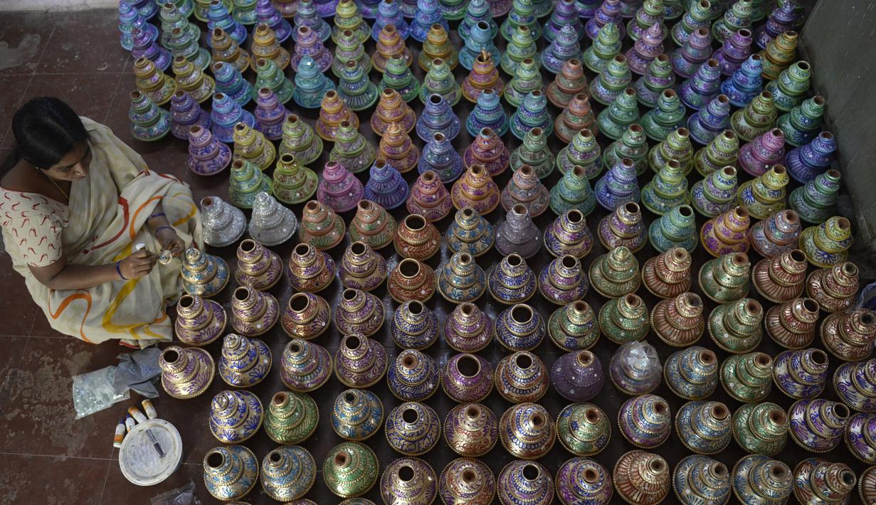 Perajin mewarnai pot minyak tembikar atau diyas menjelang Diwali, festival lampu Hindu, di sebuah lokakarya di Hyderabad (4/11/2020). Diwali yang kadang disebut Dipavali, Deepawali atau Deepavali adalah festival lampu paling terkenal yang ditunggu tiap tahunnya di India. (AFP Photo/Noah Seelam)