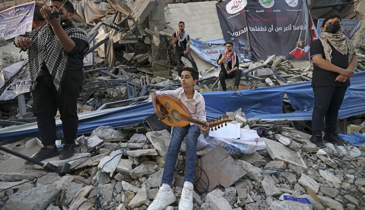 Musisi Palestina tampil di puing-puing Menara Hanadi di Kota Gaza (2/6/2021). Acara diselenggarakan oleh Komite Pemuda dan Kebudayaan Palestina lebih dari seminggu setelah gencatan senjata mengakhiri 11 hari permusuhan antara Israel dan Hamas. (AFP Photo/Mohammed Abed)