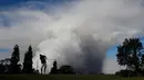 Mike Walls bermain golf saat kepulan asap abu vulkanik berembus dari puncak gunung Kiluaea di Volcano, Hawaii (21/5). Gunung Kilauea mulai meletus pada 3 Mei yang membuat sekitar 40 bangunan hangus terbakar. (AP Photo/Jae C. Hong)