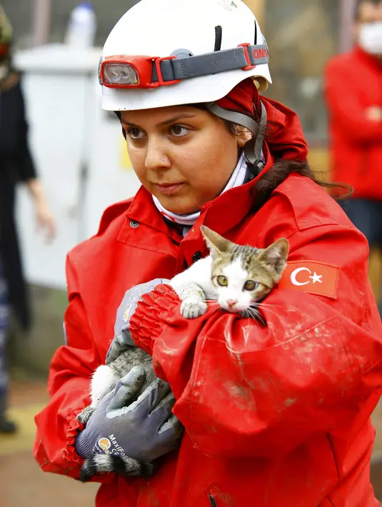 Seorang pekerja penyelamat memegang anak kucing yang dia selamatkan dari sebuah bangunan di kota Bozkurt, provinsi Kastamonu, Kamis (12/8/2021). Helikopter bergegas menyelamatkan orang-orang yang terdampar di atap rumah. (IHA via AP)
