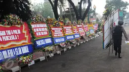 Petugas memindahkan karangan bunga yang diletakkan di depan Mabes Polri, Jakarta, Rabu (3/5). Ratusan karangan bunga itu terus berdatangan dan mengelilingi gedung Mabes Polri di Jalan Trunojoyo Jakarta Selatan. (Liputan6.com/Helmi Fithriansyah)