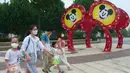 Wisatawan mengenakan masker saat berjalan di taman hiburan Disneyland, Shanghai, China, Senin (11/5/2020). Tiket untuk awal pembukaan kembali Disneyland Shanghai terjual dengan cepat pada Jumat lalu. (AP Photo/Sam McNeil)