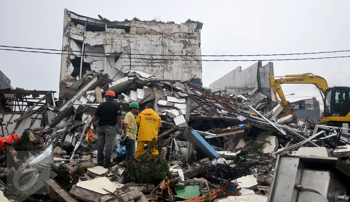 Alat berat membongkar reruntuhan bangunan PHD untuk mempermudah petugas Kepolisian melakukan proses olah TKP, Kota Bekasi, Minggu (23/10). Polisi akan melakukan olah TKP untuk memastikan penyebab ledakan tersebut. (Liputan6.com/Yoppy Renato)
