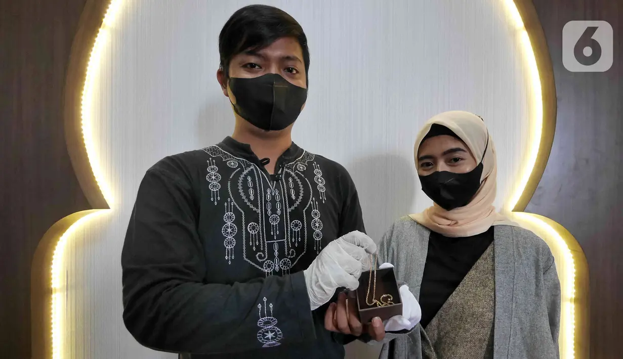 Pasangan Artahabayu dan Salwa menunjukkan mas kawin usai melangsungkan pernikahan di KUA Kecamatan Meteng, Jakarta, Selasa (22/2/2022). Sejumlah pasangan sengaja melangsungkan pernikahan pada hari ini yang memiliki tanggal, bulan, dan tahun unik yakni 22-02-2022. (Liputan6.com/Herman Zakharia)