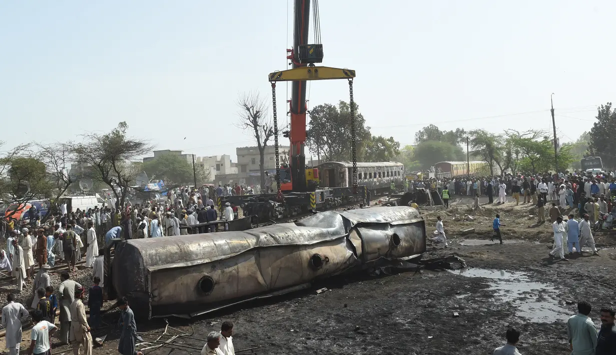 Alat berat saat akan mengevakuasi salah satu gerbong kereta tangki minyak di lokasi kecelakaan di Distrik Sheikhupura, Punjab, Selasa (28/3). Akibat kejadian tersebut sejumlah gerbong kereta dan kendaraan hangus terbakar. (AFP Photo / Ludovic Marin)