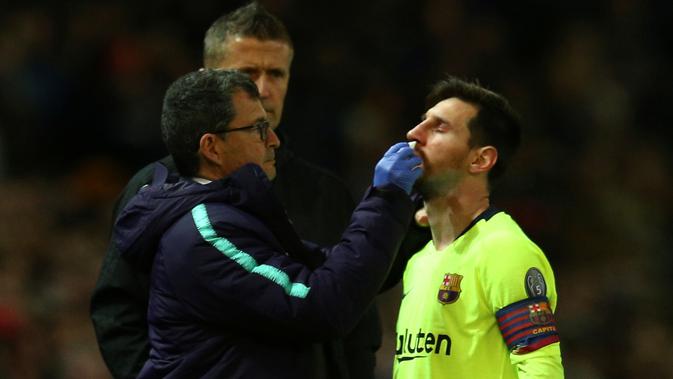 Megabintang Barcelona Lionel Messi mendapat perawatan usai ditabrak bek Manchester United (MU) Chris Smalling pada leg pertama perempat final Liga Champions di Old Trafford, Kamis (11/4/2019). (AP Photo/Dave Thompson)