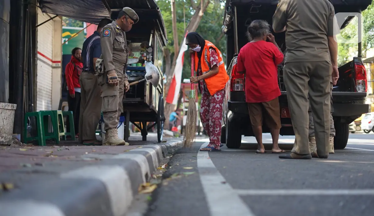 Petugas Satpol PP memberikan sanksi menyapu kepada warga yang tidak menggunakan masker di kawasan Pasar Baru, Jakarta, Jumat (21/8/2020). Sanksi tersebut dilakukan sebagai bagian dari upaya pencehagan penyebaran virus covid-19. (Liputan6.com/Immanuel Antonius)