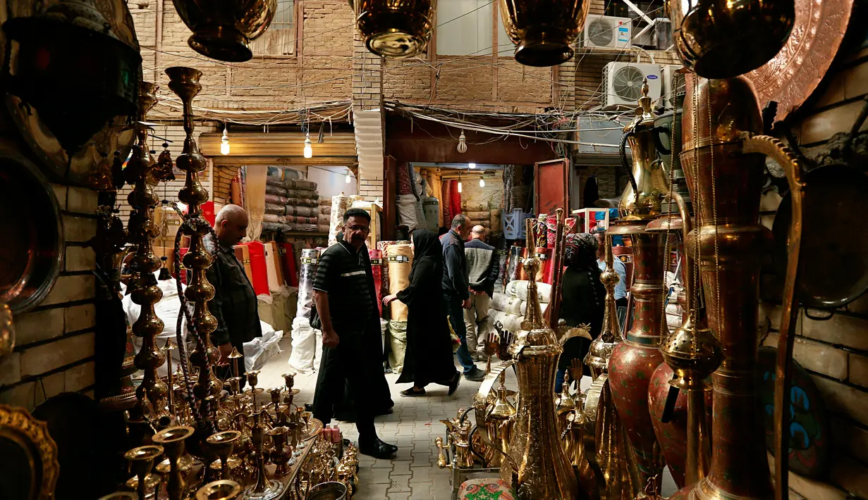 <p>Warga lalu lalang melintasi toko barang antik di Baghdad, Irak, Rabu (20/3). (AP Photo/Hadi Mizan)</p>
