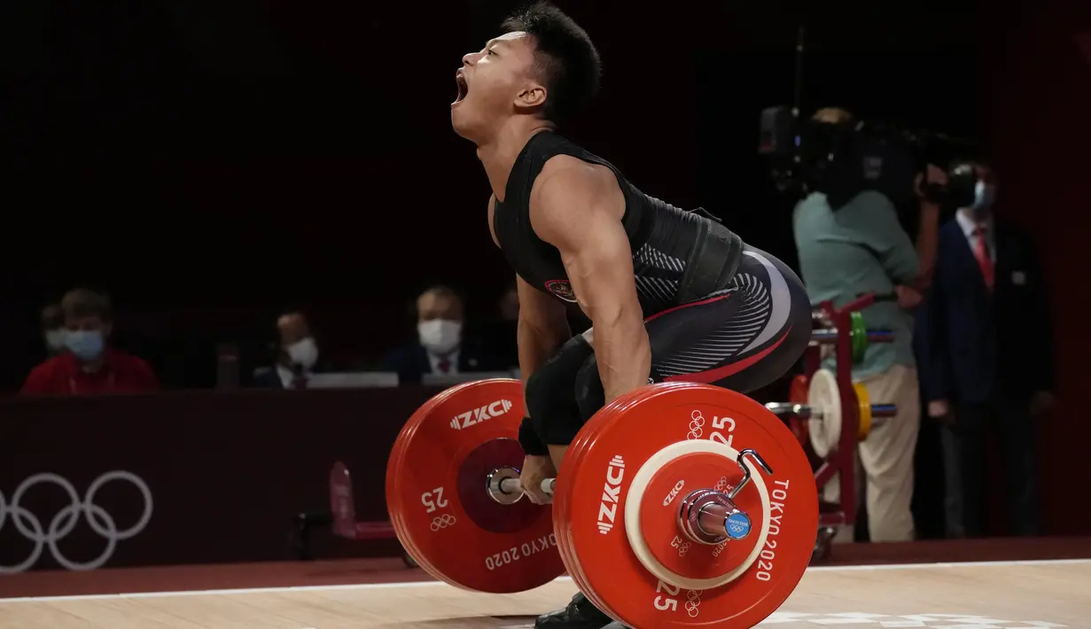 Lifter Indonesia Rahmat Erwin Abdullah saat berlaga dalam cabang olahraga angkat besi 73 kg putra pada Olimpiade Tokyo 2020 di Tokyo, Jepang, Rabu (28/7/2021). Lifter 20 tahun itu kalah bersaing dengan lifter China Shi Zhiyong dan Mayora Pernia Julio Ruben dari dari Venezuela. (AP Photo/Luca Bruno)