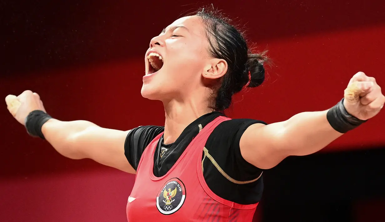 Reaksi lifter putri Indonesia Windy Cantika Aisah usai bertanding dalam cabang angkat besi nomor 49 kg Putri Grup A Olimpiade Tokyo 2020 di Tokyo International Forum, Sabtu (24/7/2021). Windy Cantika mempersembahkan medali perunggu dengan total angkatan 194 Kg. (Vincenzo PINTO/AFP)