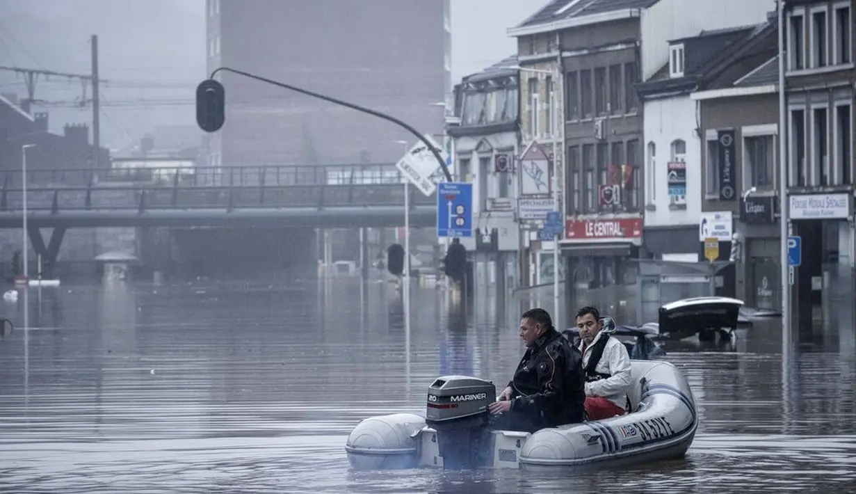 Warga menggunakan rakit karet di tengah banjir setelah Sungai Meuse jebol saat banjir besar di Liege, Belgia, Kamis (15/7/2021). Banyak orang hilang saat air naik dan menyebabkan beberapa rumah runtuh. (AP Photo/Valentin Bianchi)