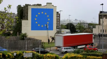 Kendaraan melintas dekat mural karya seniman jalanan Banksy di dekat terminal feri Dover, Kent, Inggris, Senin (8/5). Mural itu melukiskan seorang pria yang menaiki tangga dan menggugurkan salah satu bintang di bendera Uni Eropa. (Gareth Fuller/via AP)