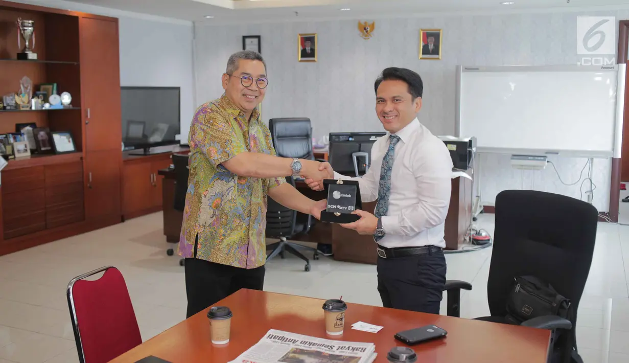 Sekretaris SCM Gilang Iskandar memberikan plakat kepada Biro Komunikasi dan layanan Informasi Kementerian Keuangan Nufransa Wira Sakti usai beraudensi di Gedung Djuanda 1, Jakarta, Selasa (1/10/2019). Pertemuan tersebut membahas kerja sama di bidang sektor media. (Liputan6.com/Faizal Fanani)