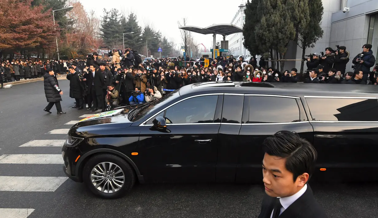 Mobil yang membawa jenazah Jonghyun SHINee keluar dari rumah persemayaman di Asan Hospital, Seoul menuju tempat pemakaman, Kamis (21/12). Ratuhan fans ikut mengantar pelepasan jenazah Jonghyun SHINee dengan isakan tangis. (JUNG Yeon-Je/AFP)