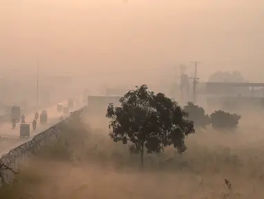 Orang-orang bepergian di sepanjang jalan di tengah kondisi kabut asap tebal di Lahore, Pakistan, Kamis (18/11/2021). Lahore telah dinyatakan sebagai kota dengan tingkat polusi udara tertinggi di dunia saat kabut asap beracun tebal melanda kota tersebut. (Arif ALI/AFP)