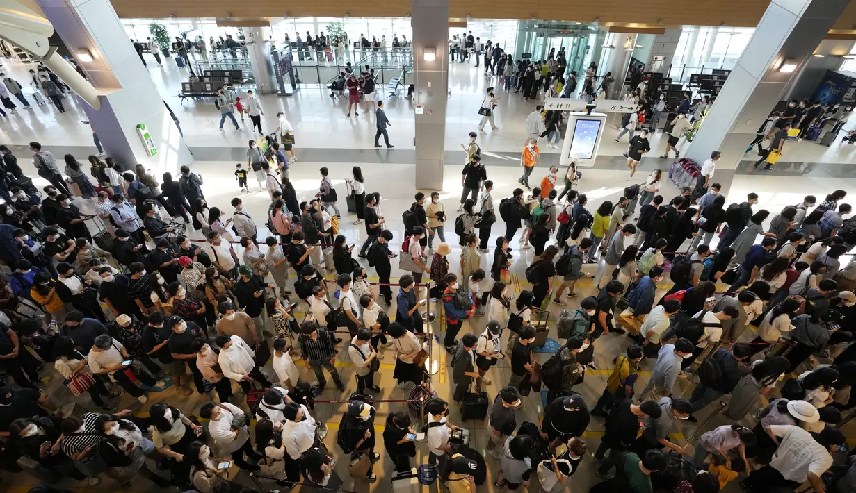Penumpang yang mengenakan masker sebagai tindakan pencegahan terhadap virus corona berbaris untuk naik pesawat menjelang liburan Chuseok, Hari Thanksgiving versi Korea di terminal penerbangan domestik bandara Gimpo di Seoul, Korea Selatan (18/9/2021). (AP Photo/Ahn Young-joon)