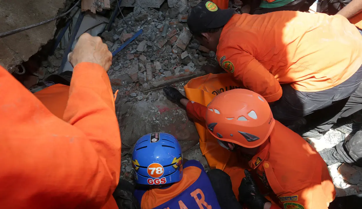 Petugas mencari korban gempa di reruntuhan bangunan menyusul gempa 6,4 SR di Kabupaten Pidie Jaya, Aceh, (7/12). Seperti dirilis BMKG, gempa berkekuatan 6,4 SR mengguncang Aceh sekitar pukul 05.03 WIB. (Antara Foto/Irwansyah Putra/via REUTERSReuters)