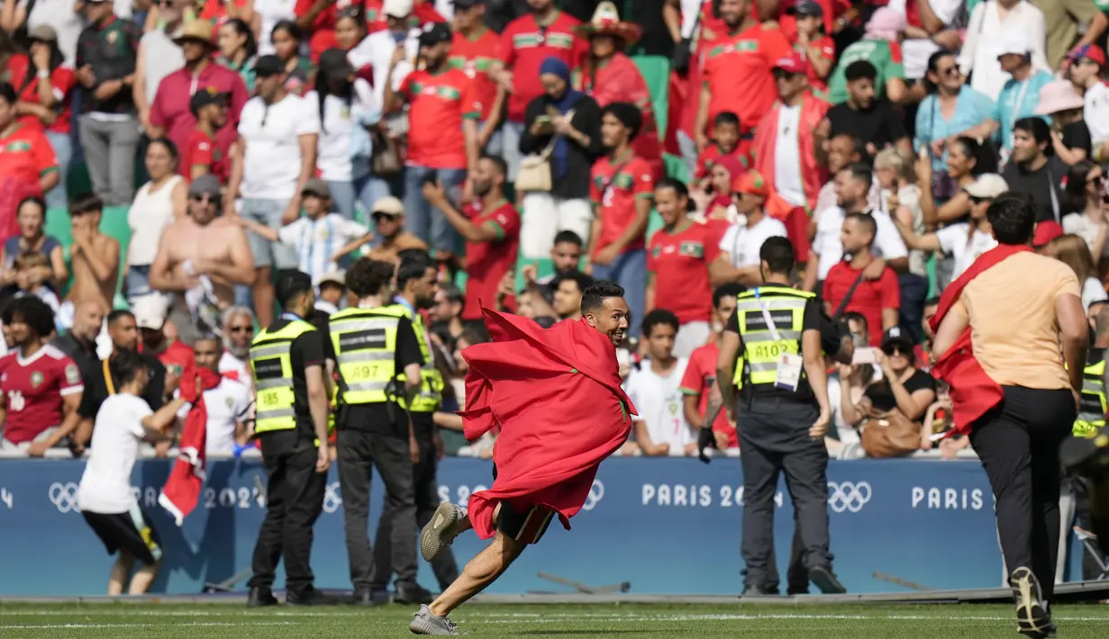 Suporter Maroko yang masuk ke dalam lapangan membuat pertandingan akhirnya terpaksa ditangguhkan selama 2 jam. Hingga laga berakhir Maroko mampu mempertahankan kemenangan dengan skor 2-1. (AP Photo/Silvia Izquierdo)