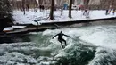 Seorang pria menaklukkan ombak saat berselancar di Sungai Eisbach selama hari musim dingin di Munich, Jerman, 4 Januari 2017. Eisbach merupakan sungai buatan dengan panjang dua kilometer dan arusnya pun merupakan buatan. (Mark RALSTON/AFP)
