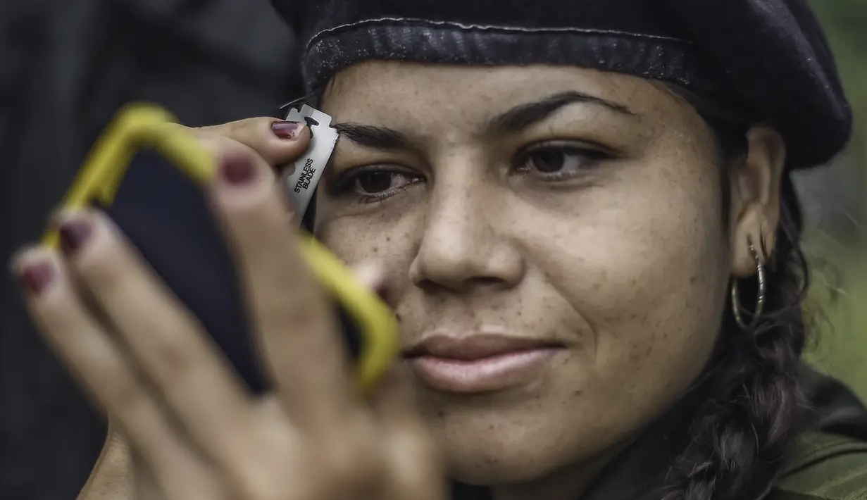 Seorang gerilyawati FARC sedang merapikan alisnya di kamp Magdalena Medio, Kolombia (15/3/2016). Gerilyawati FARC dikenal lebih sadis terhadap musuh daripada pasukan gerilyawan. (AFP Photo/Luis Acosta)