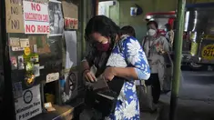 Seorang wanita memegang kartu vaksinasinya sebelum menaiki jip penumpang di sebuah terminal di kota Quezon, Senin (17/1/2022). Pemerintah Filipina melarang orang yang belum menerima vaksin COVID-19 untuk naik transportasi umum di ibu kota Manila mulai Senin ini. (AP Photo/Aaron Favila)