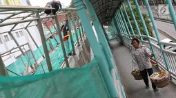 Seorang pedagang melihat pembangunan JPO Pasar Rumput di Jakarta, Selasa (15/1). Pembangunan jembatan di bangunan pasar yang terintegrasi dengan rusun tersebut dibuat untuk memudahkan mobilitas warga. (Liputan6.com/Immanuel Antonius)