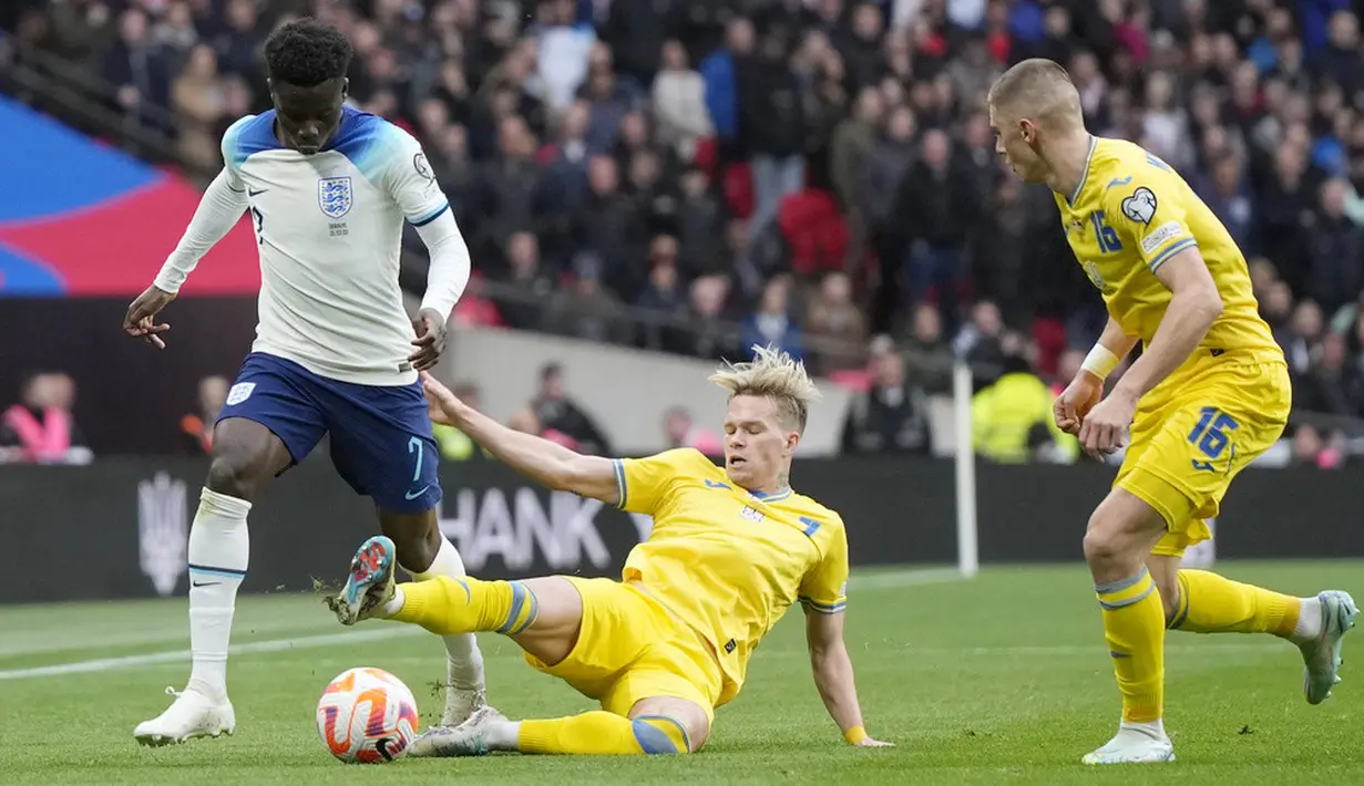 Pemain Inggris, Bukayo Saka, berusaha melewati adangan pemain Ukraina, Mykhailo Mudryk, pada laga Kualifikasi Euro 2024 Grup C di Stadion Wembley, Minggu (26/3/2023). Dua gol kemenangan Inggris atas Ukraina masing-masing lewat aksi Harry Kane dan Bukayo Saka. (AP Photo/Alastair Grant)