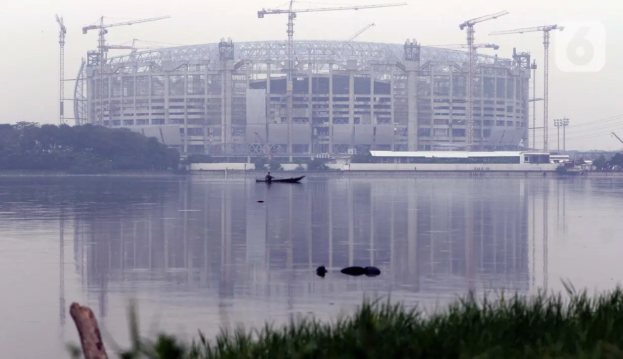 Warga memancing menggunakan perahu di Waduk Cincin yang berlatar pembangunan Jakarta International Stadium (JIS), Sabtu (19/6/2021). Pembangunan JIS sudah memasuki tahap pemasangan rangka atap dengan bentang mencapai 269 meter dan ditarget selesai Desember 2021. (Liputan6.com/Helmi Fithriansyah)