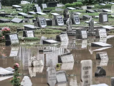 Kondisi Taman Pemakaman Umum (TPU) Karet Bivak, Jakarta, saat terendam banjir, Minggu (7/2/2021). Hujan deras yang mengguyur sejak Minggu dinihari menyebabkan tiga blok di kompleks pemakaman TPU Karet Bivak terendam banjir hingga ketinggian mencapai 30 sentimeter. (merdeka.com/Iqbal Nugroho)