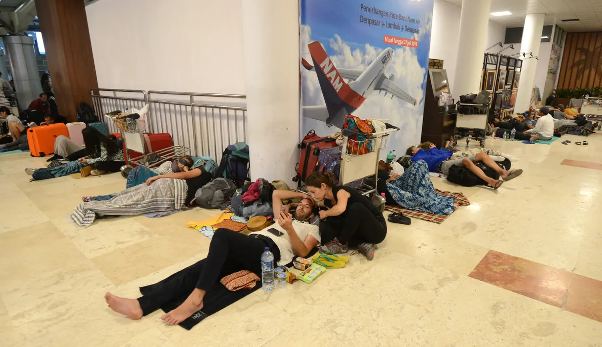 Wisatawan asing tidur di lantai saat menunggu jadwal keberangkatan pesawat di Bandara Internasional Praya Lombok, NTB, Senin (6/8). Imbas gempa 7 SR, para wisatawan terlantar di bandara karena jam pemberangkatan pesawat yang tertunda (AFP/SONNY TUMBELAKA)