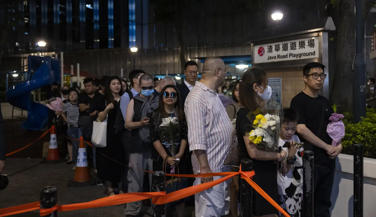 Para penggemar penyanyi dan penulis lagu Coco Lee, berkumpul dengan membawa bunga untuk memberikan penghormatan kepada idola mereka di pemakamannya di Hong Kong pada hari Senin. (AP Photo/Louise Delmotte)