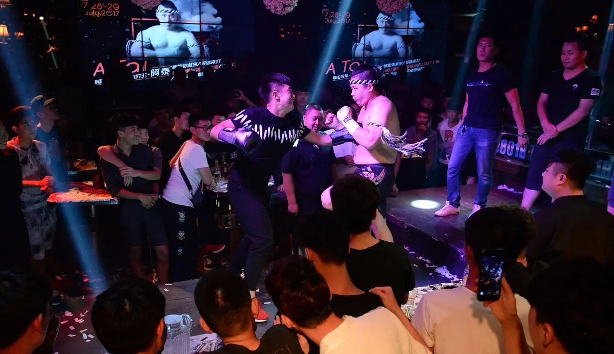 Seorang pengunjung memukul dada petinju Muay Thai pada sebuah pertandingan di bar kawasan Handan, Kota Hebei, Tiongkok, 29 Juli 2017. Pertandingan Muay Thai ini sengaja digelar untuk memberikan layanan 'pukulan gratis' bagi pengunjung yang stres (STR/AFP)