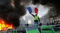 Demonstran mengibarkan bendera Prancis saat kerusuhan menentang kenaikan harga bahan bakar di Paris, Prancis, Sabtu (24/11). Demonstrasi terjadi oleh dorongan gerakan "rompi kuning". (AP Photo/Michel Euler)