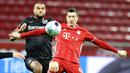 Striker Bayern Munchen, Robert Lewandowski, berebut bola dengan pemain Bayer Leverkusen, Jonathan Tah, pada laga Bundesliga di Stadion BayArena, Minggu (20/12/2020). Bayern Munchen menang dengan skor 2-1. (Bernd Thissen/Pool Photo via AP)