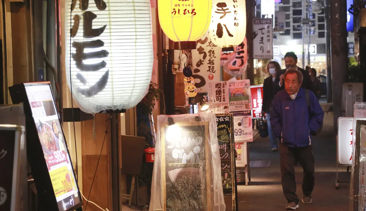 Orang-orang melintasi jalan di Tokyo, Jepang, Senin (25/10/2021). Orang-orang di Tokyo dapat makan dan minum di bar dan restoran mulai Senin malam ketika aturan jarak sosial dilonggarkan karena kasus COVID-19 harian di negara itu mencapai level terendah dalam setahun lebih. (AP Photo/Koji Sasahara)