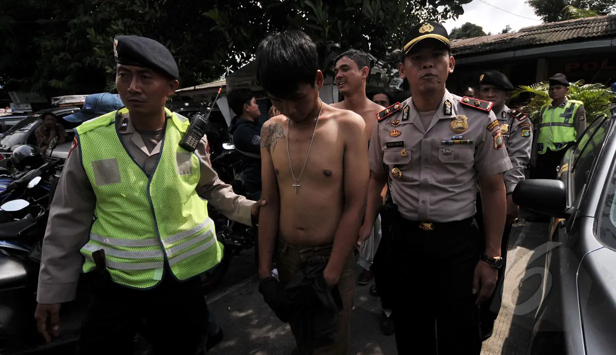 Sejumlah petugas mengamankan salah satu preman di kawasan terminal Pulogadung,Jakarta, Kamis, (12/3/2015).  Petugas berhasil menyita minuman keras, senjata tajam, dan belasan orang yang diduga preman di lokasi tersebut. (Liputan6.com/Johan Tallo)