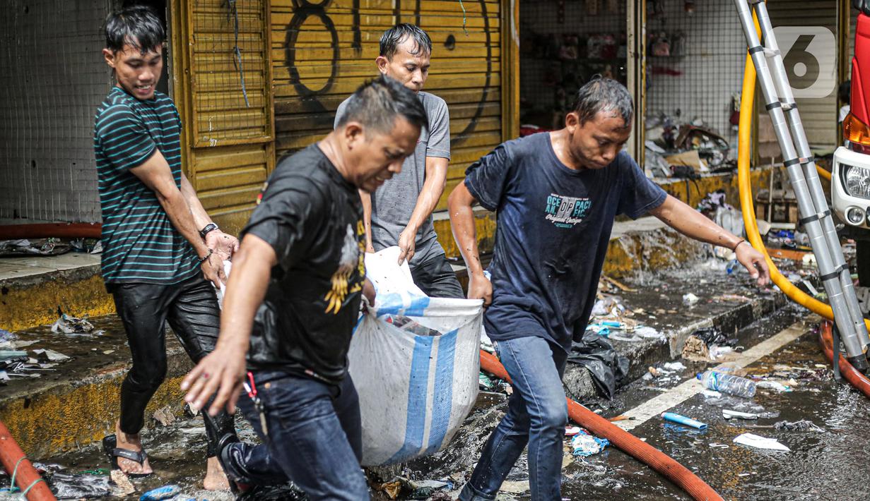 Pedagang menyelamatkan barang dagangan saat proses pendinginan oleh damkar dari kebakaran di Pasar Pagi Asemka, Jakarta, Jumat (18/11/2022). Menurut Kepala Sektor Tambora Sudin Gulkarmat Jakarta Barat, Joko Susilo, api menghanguskan sekitar 20 lapak pedagang. (Liputan6.com/Faizal Fanani)